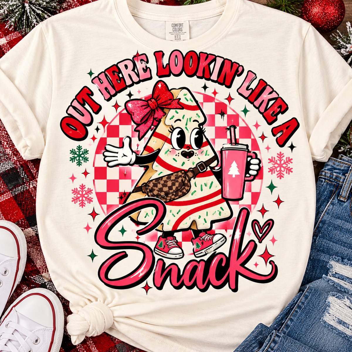 Cream T-shirt mockup with a playful Christmas tree cake character and Out Here Lookin' Like a Snack holiday design